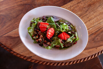 Overhead view of strawberry salad on wood table