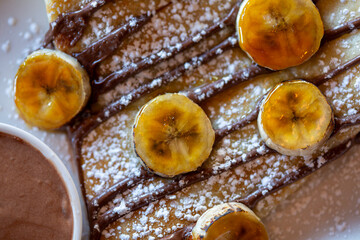 Close up view of a crepe with banana slices and chocolate drizzle