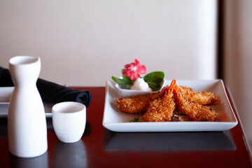 Plate of tempura fried shrimps with sake on table