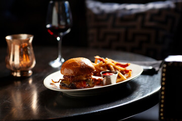 A meat lovers burger and side of fries on dark table