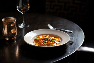 Side view of ravioli in a shallow bowl on dark table