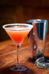 An orange colored cocktail in martini glass vertical