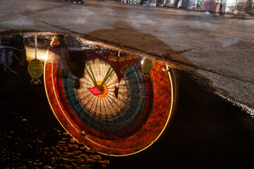 Long exposure of ferris wheel reflected in puddle