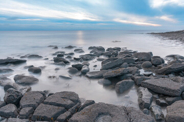 Calm Twilight on Rocky Shoreline With Gentle Waves Lapping Against Stones at Dusk
