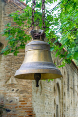 Obraz premium An old ornamented bronze bell hangs on a rusty chain near a church