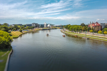 Fototapeta premium Landscape of a lake surrounded by a forest and a river flowing through the city.