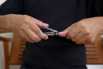 Fototapeta premium Close up shot of hands cutting nails with nail cutter