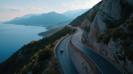 Fototapeta premium A scenic coastal road curves around mountains, overlooking a serene bay, capturing the essence of a picturesque drive.