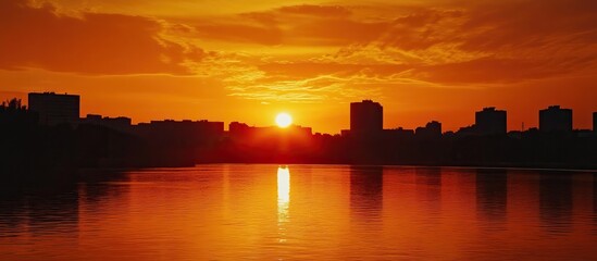Silhouetted Cityscape at Sunset Over a Calm River
