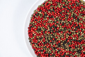 A mixture of different peppercorns on a white background, top view, copy space for text