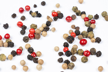 Red, green, white and black peppercorns on a white background