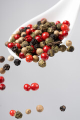 Different types of peppercorns pouring. Red, green, white and black pepper.