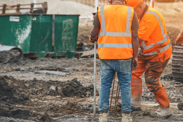 Construction workers in bright vests collaborate on busy site during a sunny afternoon shift