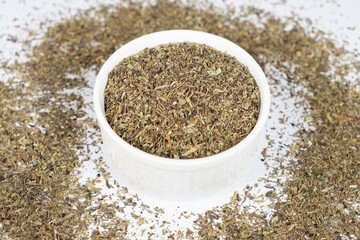 Seasoning dried basil in a plate, chopped basil close-up