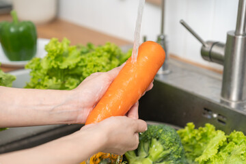 Close up asian young woman washing carrot, tomato, broccoli  fresh vegetables, paprika with splash...