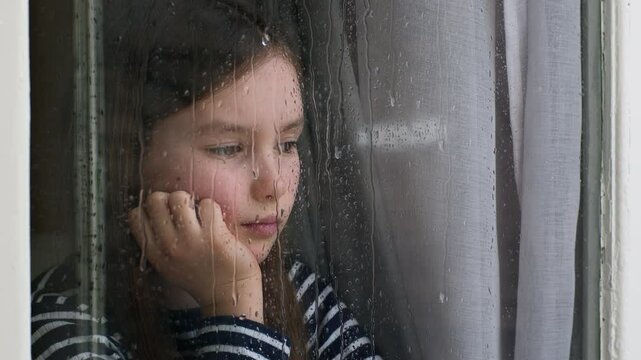 Caucasian little girl looking out window rainy weather dropping sadness anxiety stress crisis divorce unhappy child offspring kid psychological trauma descendant despondency schoolgirl pupil lonely
