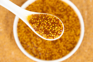 Traditional French Dijon mustard in a spoon on a white background