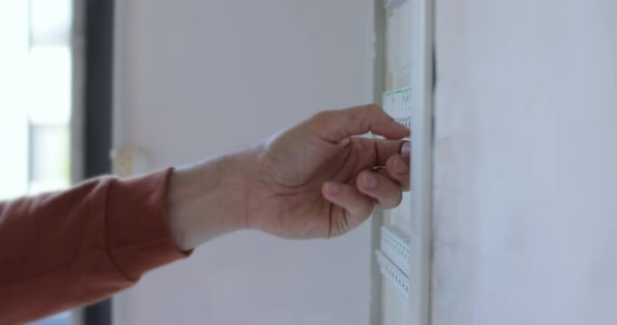 Man check and turn off circuit breakers in electrical fuse box at house.