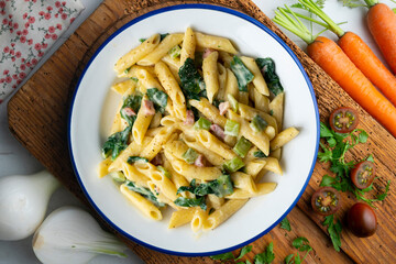 Italian macaroni with chard, ham and cream sauce. Top view table with  decorations.