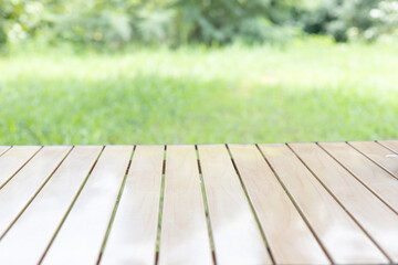 Wood table in outdoor setting lush green grass on lawn. smooth, clean planks under the bright sunlight, reflection polished surface, the natural texture in this peaceful scene of backyard nature.