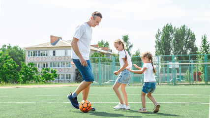 Father and daughters playing in the sport stadium at the daytime. Concept of friendly family....