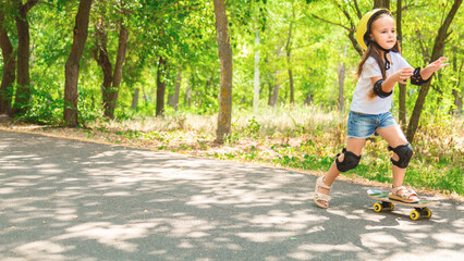 Girl skateboard with safety equipment - helmet, knee and elbow pads. Safe summer activity. Kids activity.