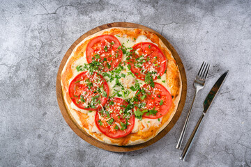 Neapolitan Margherita pizza with tomatoes, mozzarella, basil and olives on stone table