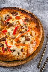 Pizza with paprika and roast beef on cutting board on stone table