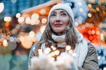 A serene moment of joy as a woman enjoys festive lights in a snowy winter market at night