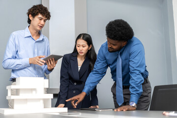 Architects engineers collaborating on building design project in modern office, diverse team of professionals female muslim architect and male engineers discussing architectural model of structure