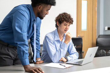 Obraz premium Diverse team of business professionals working on laptops during corporate meeting analyzing data and discussing project strategies, focused on collaboration, productivity and effective communication