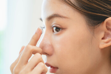 Close-up shot of woman putting contact lens in her eyes