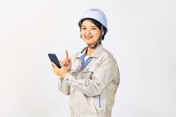 スマホを使うヘルメットと作業服を着た女性　作業員　エンジニア　全身写真