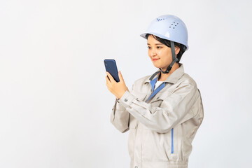 スマホを使うヘルメットと作業服を着た女性　作業員　エンジニア