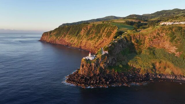 Sunrise aerial view of Arnel lighthouse perched atop Sao Miguel island headland
