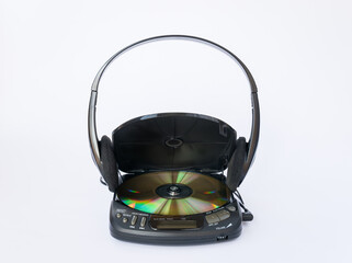 Close-up view of CD player with open lid and golden CD inside and headphones isolated on white...