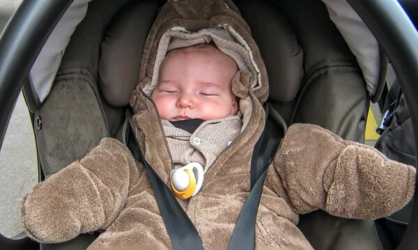B&eacute;b&eacute; dormant paisiblement dans son si&egrave;ge auto dans la voiture, v&ecirc;tu d'une grenouill&egrave;re en forme de nounours, moment de douceur et de s&eacute;curit&eacute;