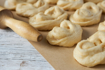 Close-up of yeast dough rolls on a baking sheet with a wooden rolling pin.