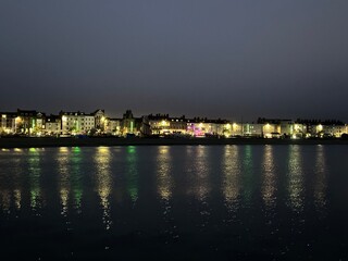 Night view of the town Weymouth with the lights reflected in Weymouth Bay water, England, United Kingdom, July 2023