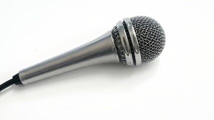 A sleek, silver microphone lies on a crisp white surface, its slender body and delicate cable creating a