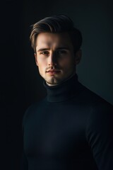 Obraz premium Stylish man in a dark turtleneck poses confidently against a shadowy background