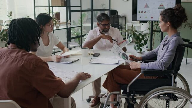 Managers and female analyst in wheelchair communicating at office