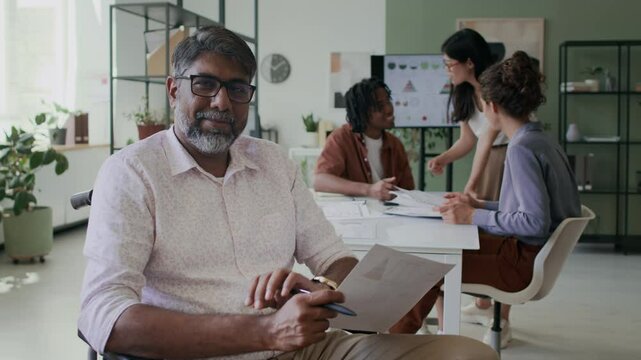 Portrait of mature businessman with disability at office with team