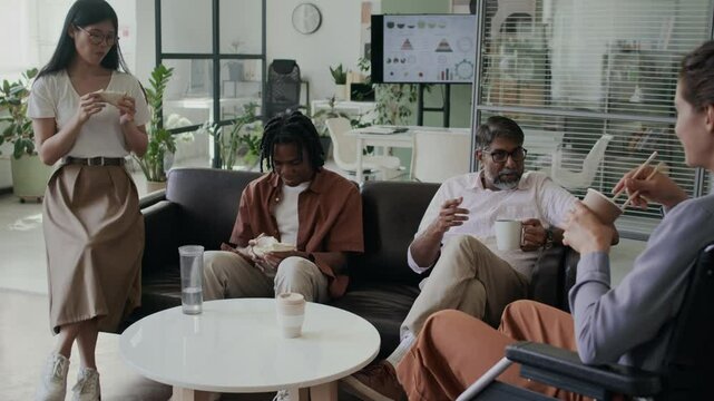 Team of multiethnic colleagues chatting during lunch at office