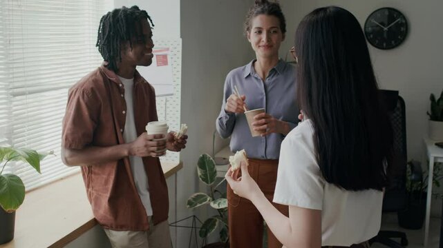Three employees talking while having lunch break at office