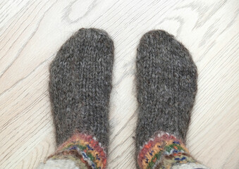 A cozy scene with Feet in warm, woolen socks on a wooden floor.