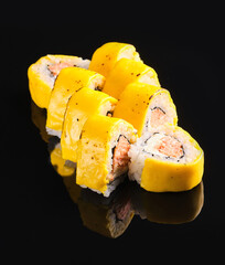 Delicious sushi rolls with vibrant yellow outer layer and savory filling on a sleek black background
