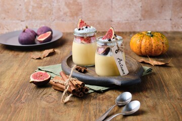 Autumn dessert, pumpkin panna cotta with chia pudding and fresh figs in jars on wooden background....