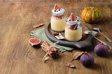 Autumn dessert, pumpkin panna cotta with chia pudding and fresh figs in jars on wooden background. Desserts without baking. Thanksgiving day