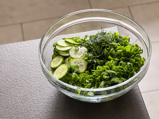 Close up of a simple green salad in a glass bowl on grey table 
